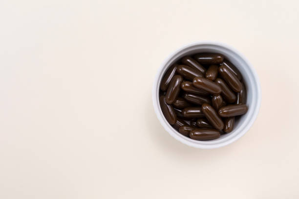 flat lay sunflower lecithin brown softgel pill capsule in white bowl on beige background. vitamin, dietary supplements. copy space. copy space. lecithin benefits for lower cholesterol. horizontal - lecithin capsule vitamin pill brown imagens e fotografias de stock