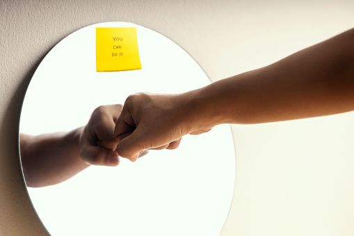 Growth Mindset Concept. Person making a Self Encouragement by Fist Bump and You Can Do It Sticky Note on Mirror