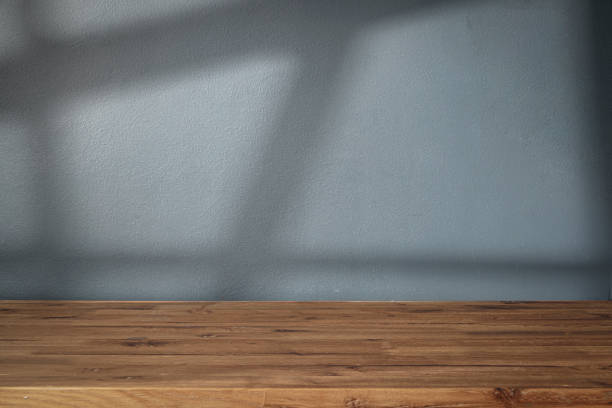 istock Table shadow background. Wooden table and white empty wall with plant shadows. 1671140105