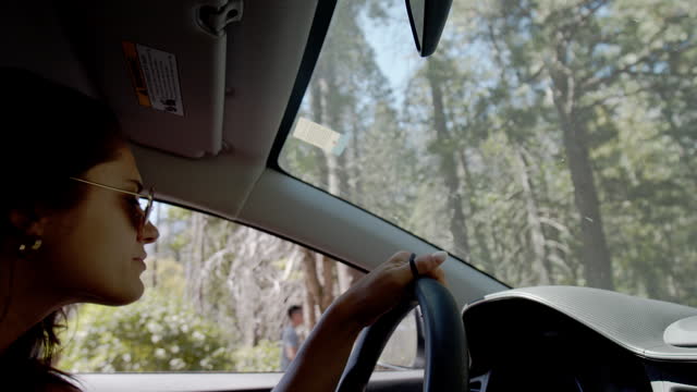 Young woman driving into Yosemite National Park in awe of the beauty in nature