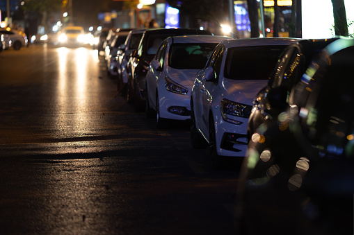 Cars standing in a row at night in parking. Urban street.