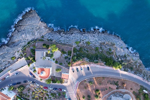 An aerial view above of a small lighthouse by the rocky coastline in Oropesa, Spain.
