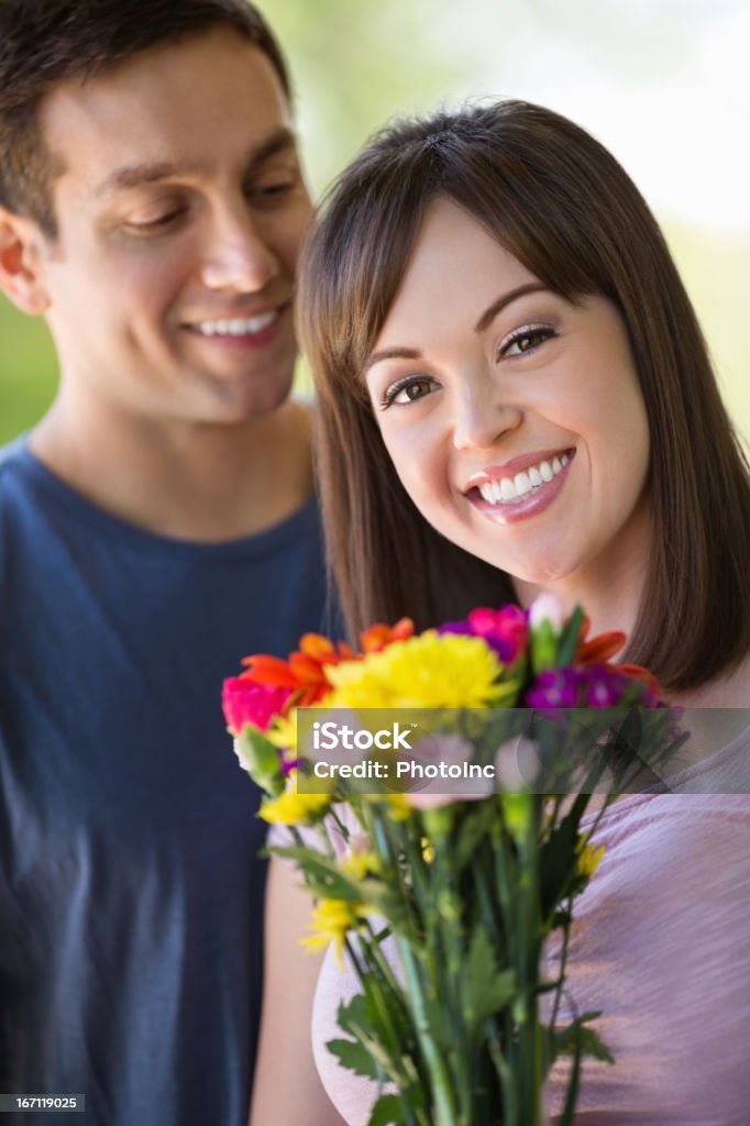 Woman With Flowers While Man Standing In Background Portrait of young woman with flowers while man standing in background 20-24 Years Stock Photo