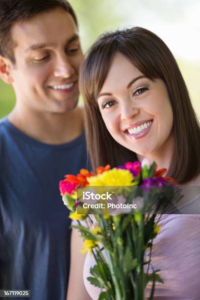 Woman With Flowers While Man Standing In Background Stock Photo - Download Image Now