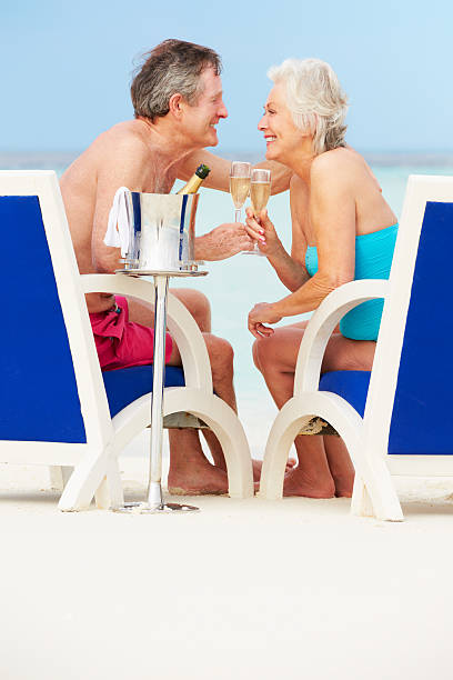 senior pareja en playa relajante en sillas bebiendo champán - men refreshment male summer fotografías e imágenes de stock