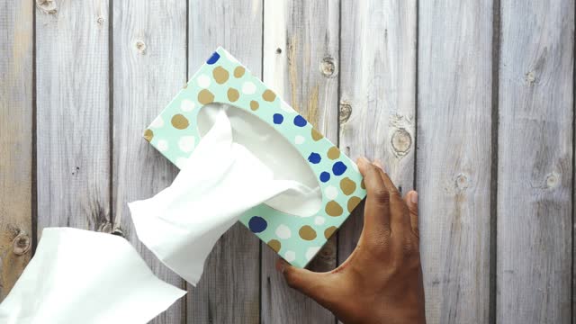 hand pull out a piece of tissue from tissue paper box