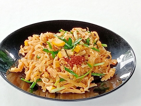 Thai Stir-Fried noodles in a black plate on white background.