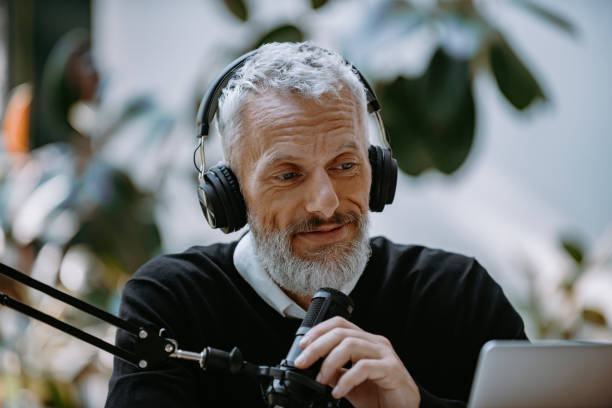 istock Confident mature presenter in headphones using microphone while recording podcast in studio 1671297622