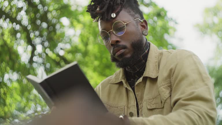 Man reading a hardcover book in the park