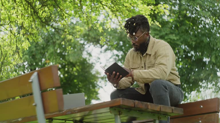 Man reading a hardcover book in the park