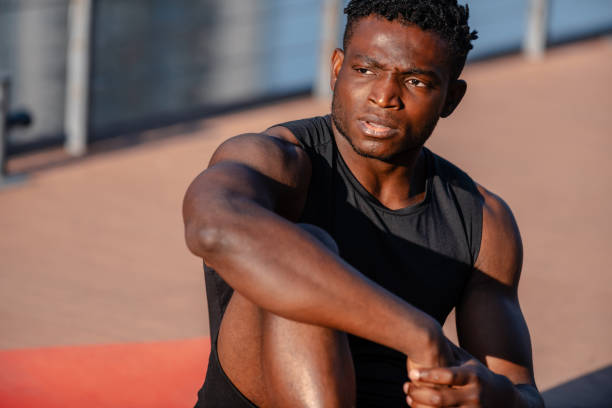 istock Confident young African man in sportswear resting after training while sitting on exercise mat outdoors 1671320528
