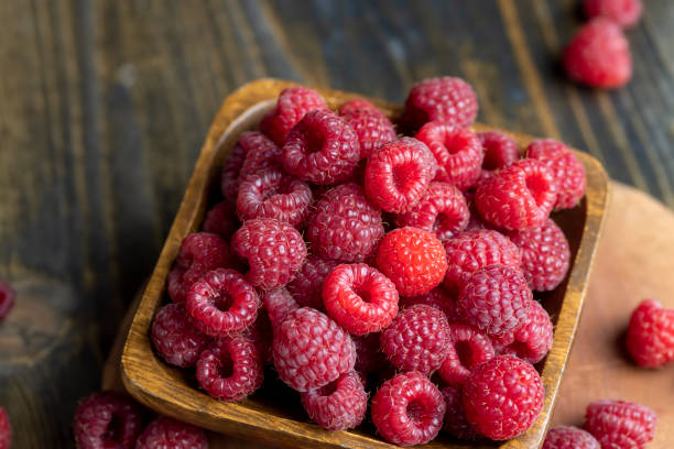 istock Ripe raspberries on a wooden board 1671325347