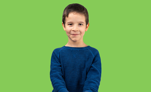 Brunette little child wearing casual t-shirt standing over isolated green background with a happy and cool smile on face. Lucky person