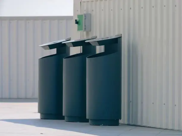The three black plastic trash cans lined up side-by-side against a white wall, AI-generated.