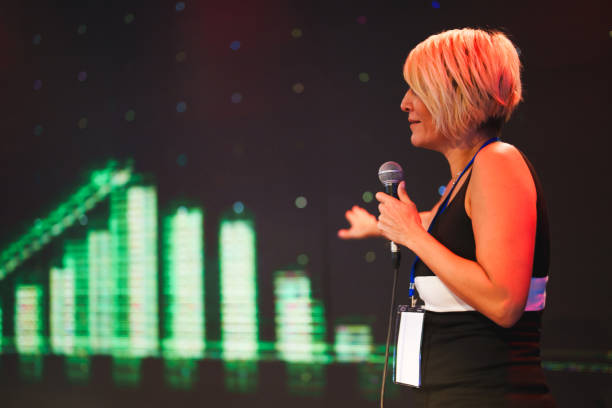 istock Speeker talking and showing a presentation to audience on stage with microphone 1671401351