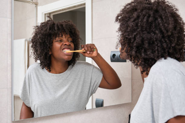 istock African woman brushing her teeth in the bathroom using ecological toothbrush. 1671402914