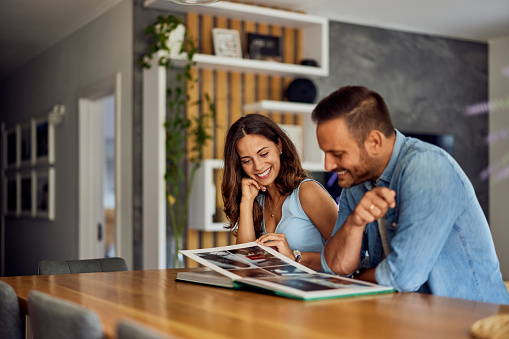 A smiling love couple going through happy memories by looking at the photo album.