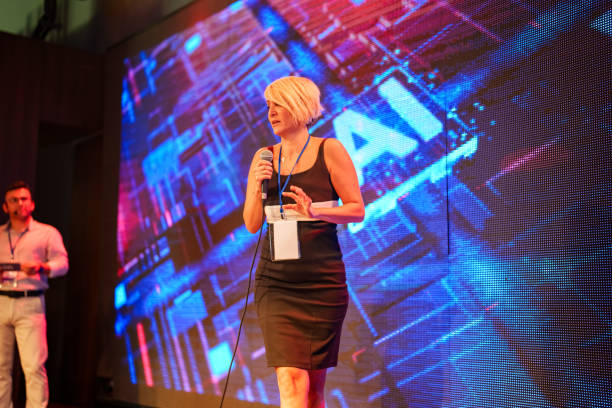 istock Speeker talking and showing a presentation to audience on stage with microphone 1671405400