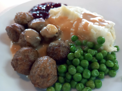 meatballs with peas, mashed potatoes and cranberry jelly on a white plate