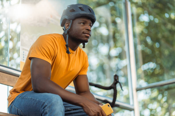 istock Smiling african american man looking away while relaxing with bicycle at the bus station 1671407021
