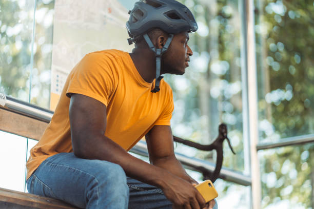 istock Happy african american man looking away and holding mobile phone while relaxing 1671407024