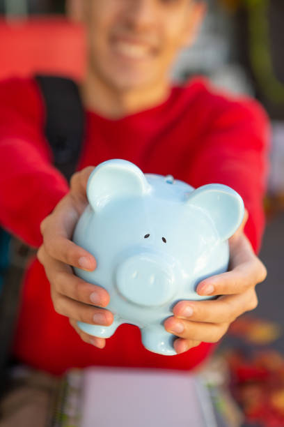 istock Happy University student holding piggy bank 1671467608
