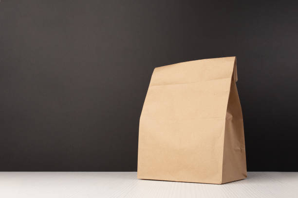 bolsa de almuerzo escolar con embalaje de papel marrón, paquete ecológico para niños en el fondo de la pizarra - packed lunch lunch paper bag blackboard fotografías e imágenes de stock