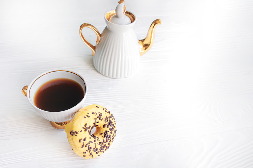 White vintage teapot and cup of coffee on white wooden background. Sweet breakfast