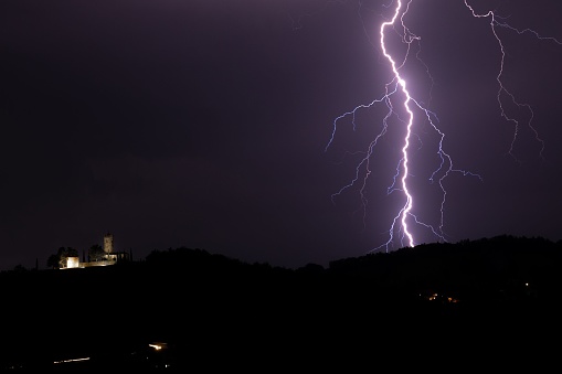 A scenic view of a lightning strike in hills at night