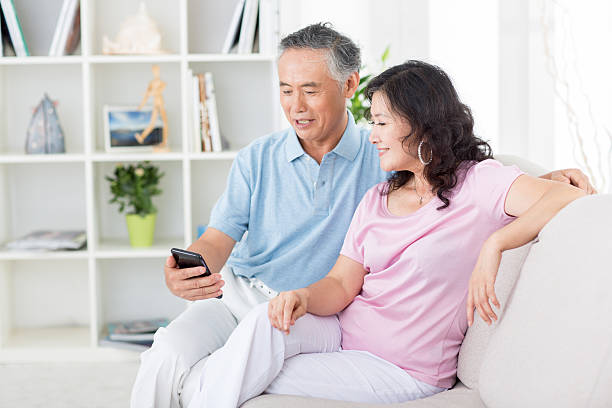 istock Two senior asian people looking at mobile phone 167154488