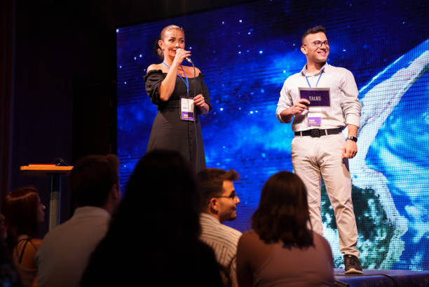 istock Speeker talking and showing a presentation to audience on stage with microphone 1671546741