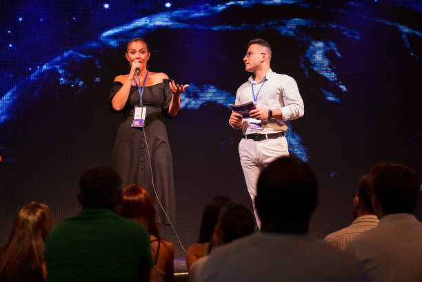istock Speeker talking and showing a presentation to audience on stage with microphone 1671549436