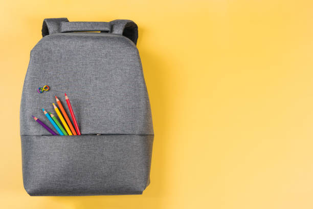 istock Gray backpack with autism infinity rainbow symbol sign, colored pencils in yellow background. Top view. World autism awareness day, autism rights movement, neurodiversity, autistic acceptance movement 1671563376