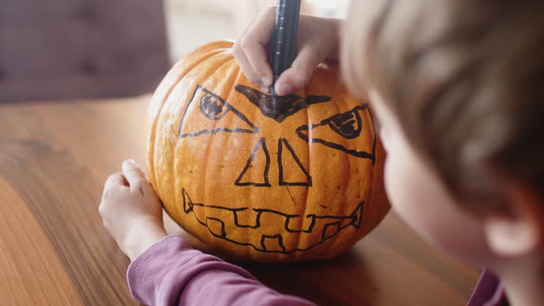 Cute little boy preparing Jack O' Lantern pumpkin for Halloween at home