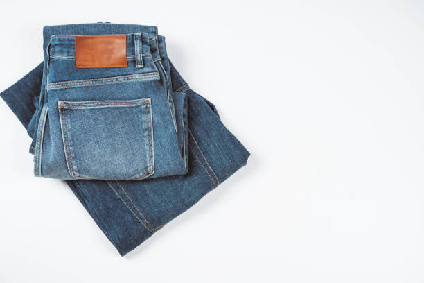 istock Folded navy blue jeans on white background. Blank brown leather label sewed on a blue denim jeans. Mock up navy jeans tag. Top view, copy space 1671569160
