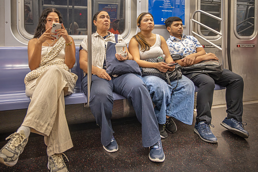 New York Subway, New York, USA - August 21th 2023: Four relaxed people sitting in a subway car