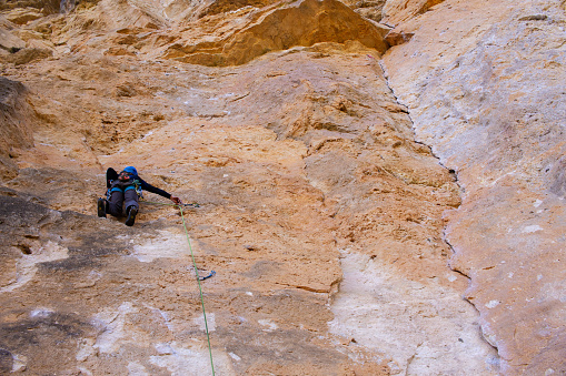 Young man climbing big rock wall in mountain