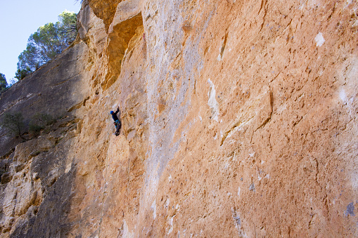 Young man climbing big rock wall in mountain