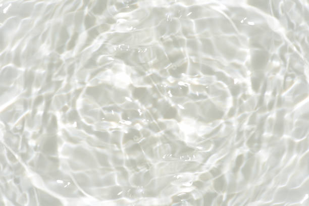 White water with ripples on the surface. Defocus blurred transparent white colored clear calm water surface texture with splashes and bubbles. Water waves with shining pattern texture background.