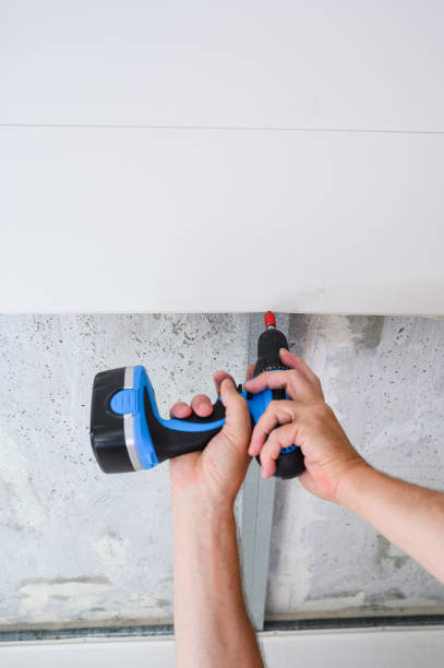 istock Close-up of a worker fastening a suspended ceiling panel with a screwdriver. 1671632802