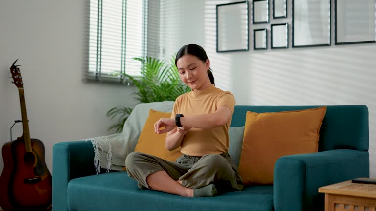 Asian woman looking and touching on smartwatch, using smart watch app and happy with goals.