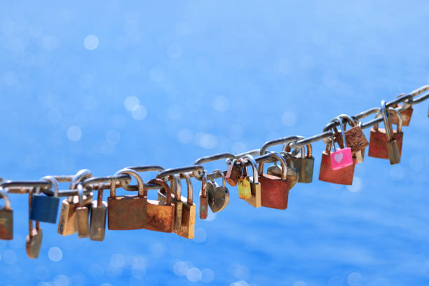 Close up of old rusty love locks on chain against background of blue sea on sunny day. Close up of old rusty love locks on chain against background of blue sea on sunny day. Trip for valentines day