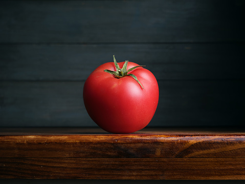 Image of Still Life with Tomato. Dark wood background, antique wooden table.