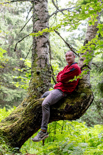 istock A young man finds reprieve, sitting on a tree branch 1671655247