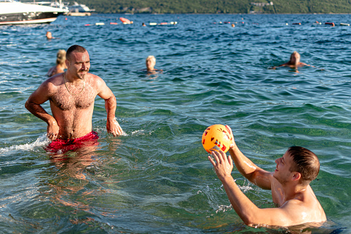 This image signifies the embrace of beach spirit as two young men play a game of volleyball in the sea