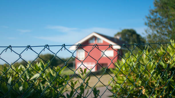 istock Red house garden  behind wire fence 1671674526
