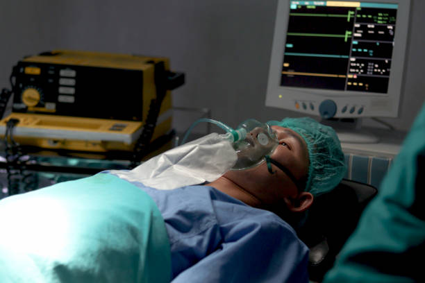 istock Patient with anesthesia mask or breathing oxygen respiratory equipment lying on operating bed. Patient be prepared for medical treatment by surgeon doctor at operating room in hospital. 1671675075