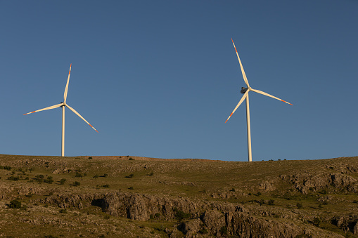 Two wind turbines against a clear blue sky on top of the mount.