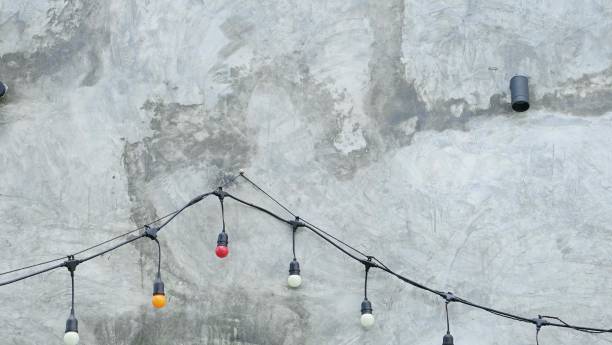 istock Decorative light bulbs hanging on the concrete wall in the city. 1671714582