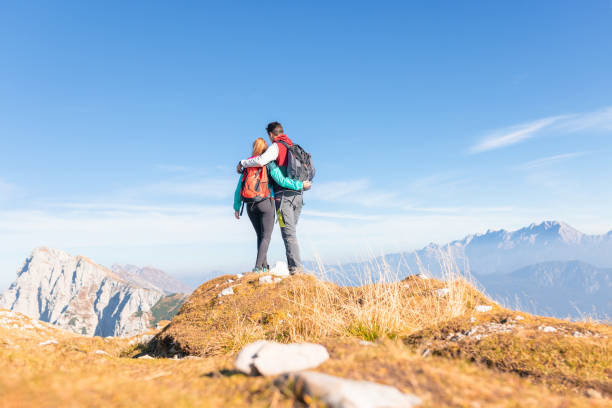 istock Hiker couple hugging and looking at the mountains 1671724585
